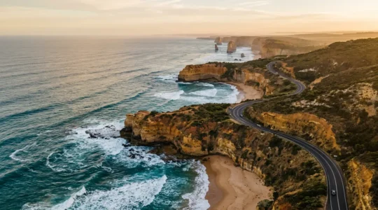 Aerial view of the Great Ocean Road hugging dramatic coastal cliffs with ocean waves below