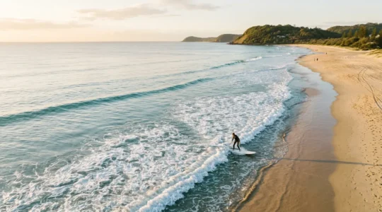 Beginner surfer riding gentle whitewash waves at a calm Gold Coast beach during golden hour