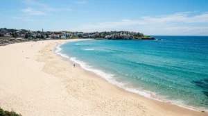 Empty Sydney beach with pristine white sand and turquoise water after heavy rainfall, showing closed beach warning infrastructure without swimmers