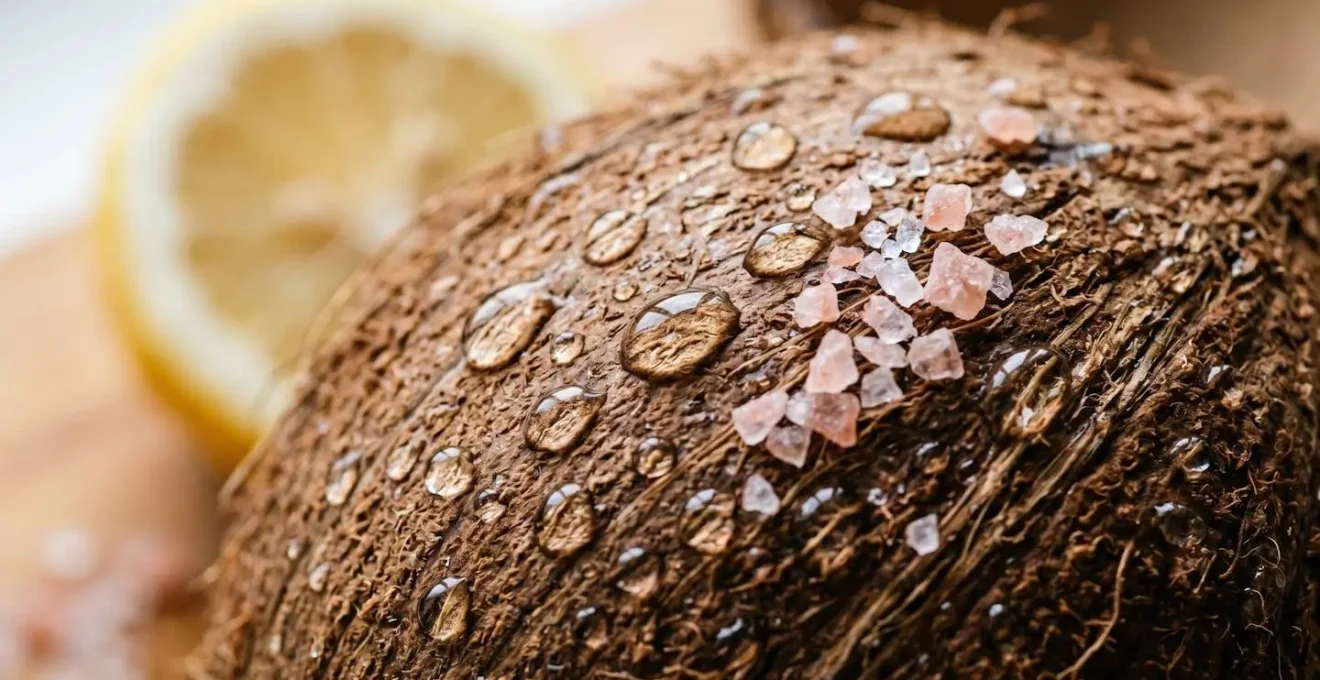 Extreme close-up macro shot of fresh coconut water droplets and natural salt crystals on textured surface with shallow depth of field