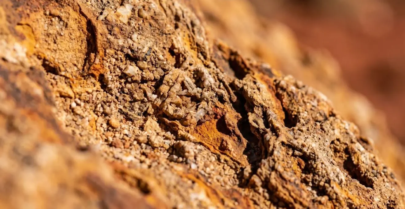 Extreme close-up of ancient sandstone textures with natural ochre patterns and weathered crevices holding sacred knowledge