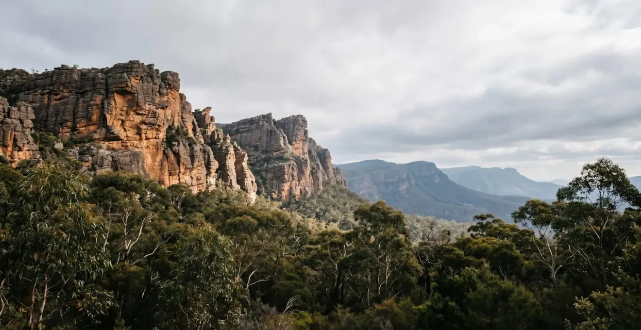Dramatic sandstone cliff formations in Grampians National Park with native vegetation and distant ranges